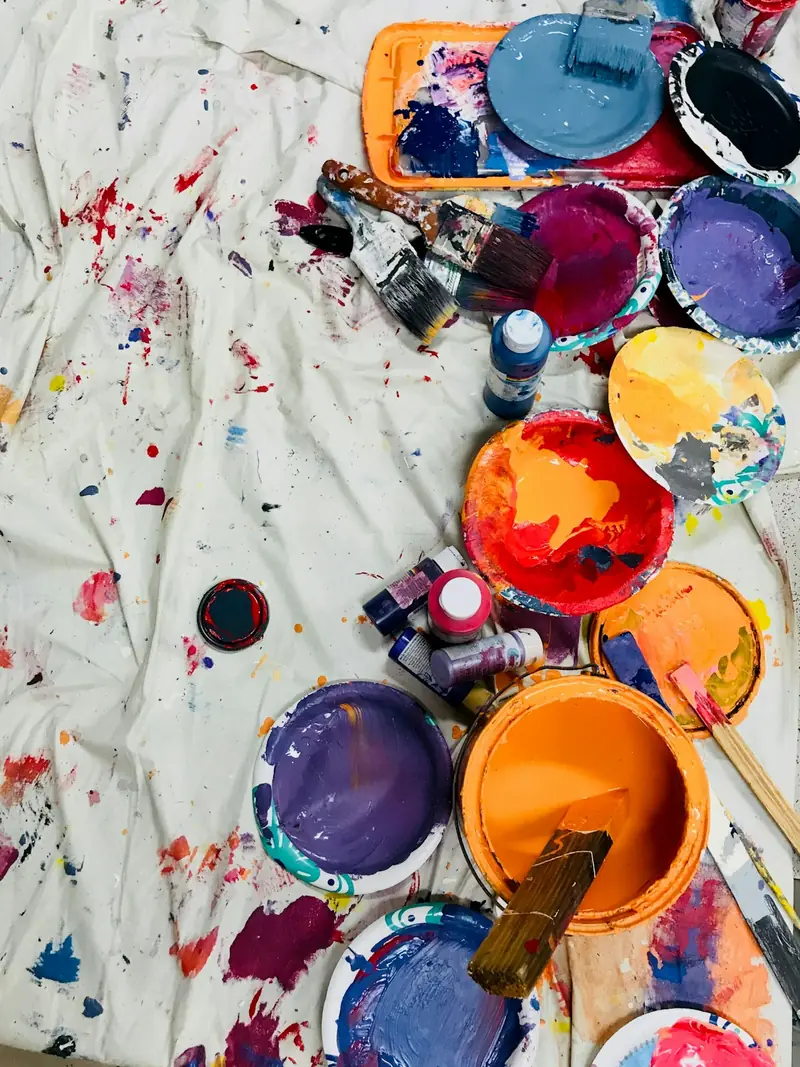 Tarros de pintura de colores abiertos sobre una tela manchada